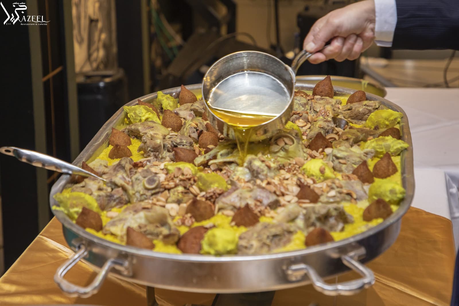 A large tray of ouzi — lamb over spiced rice with nuts — being finished at the table